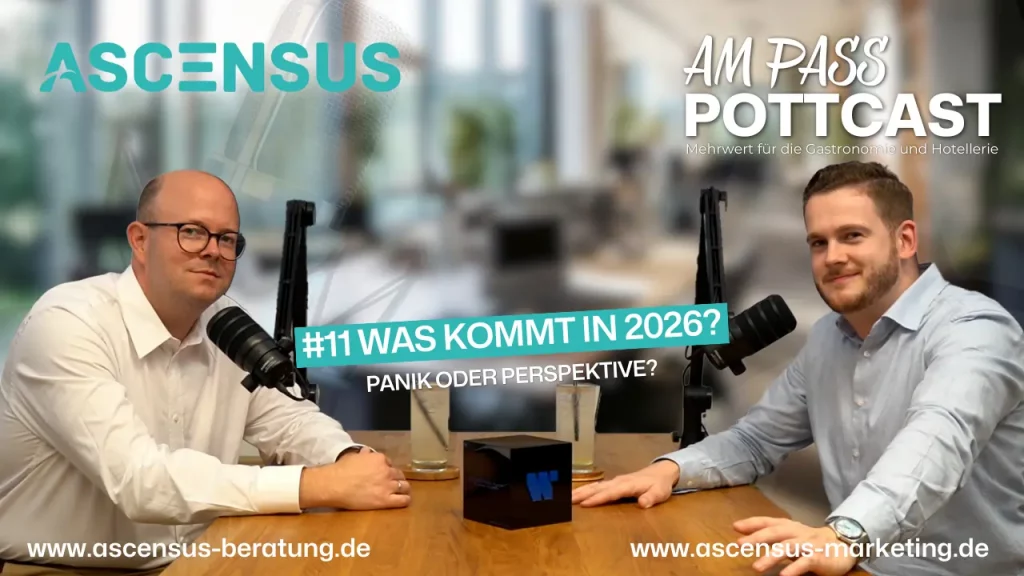 Zwei Männer sitzen an einem Tisch mit Mikrofonen, scheinbar in einer Podcast-Aufnahme