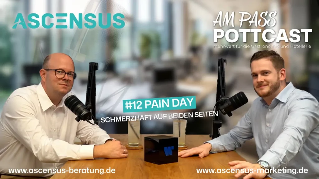 Zwei Männer sitzen an einem Tisch mit Mikrofonen, scheinbar in einer Podcast-Aufnahme